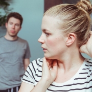 A woman adjusts her hair as a man stands in the background