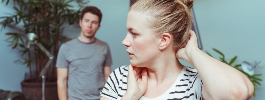 A woman adjusts her hair as a man stands in the background