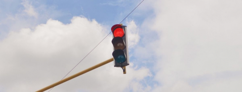 Red traffic light against clouds in the sky