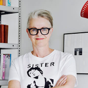 The workshop tutor, a woman, at home against a bookshelf.