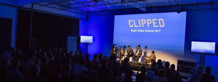 A panel of speakers in front of a festival audience.
