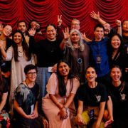 Episode One participants, Shuchi Kothari, and Dale Corlett stand in front of a red curtain and PASC banner