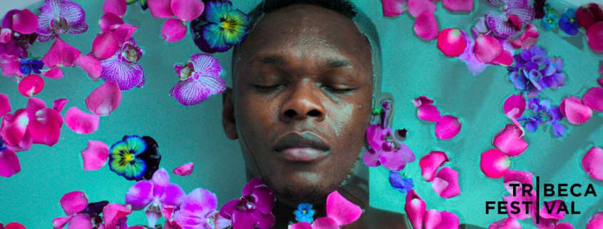 Israel Adesanya lays with eyes closed in a bath sprinkled with flower petals